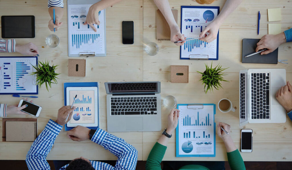 foto met mensen aan een tafel en charts en laptops